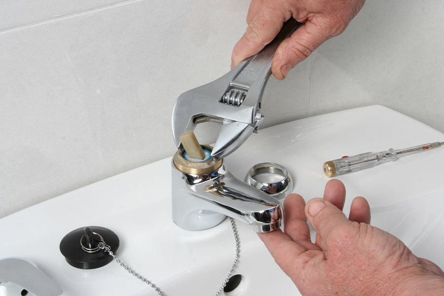 Fixing a bathroom faucet with wrench.